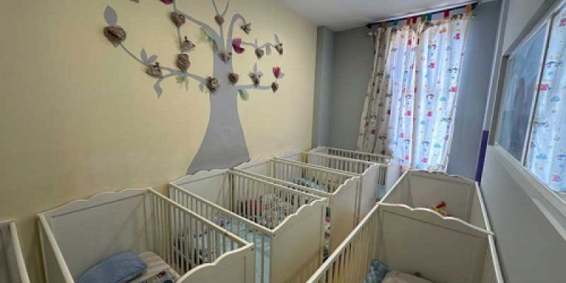Habitación con cunas decorada con un árbol de papel en la pared
