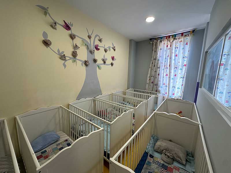Habitación con cunas decorada con un árbol de papel en la pared